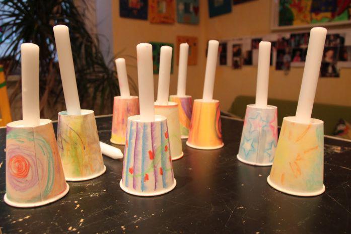 Neun Pappbecher auf einem Tisch auf den Kopf gestellt, auf jedem Becher eine Kerze, alle auf dem Tisch platziert.