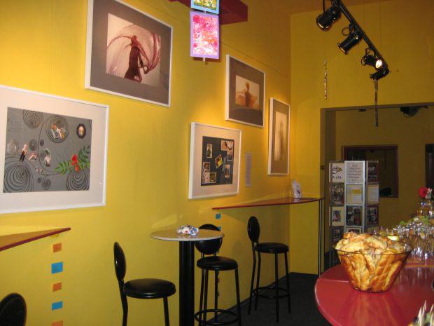 Eine gelbe Küchenwand mit fünf Bildern, davor Stühle und ein Tisch mit verschiedenen Speisen