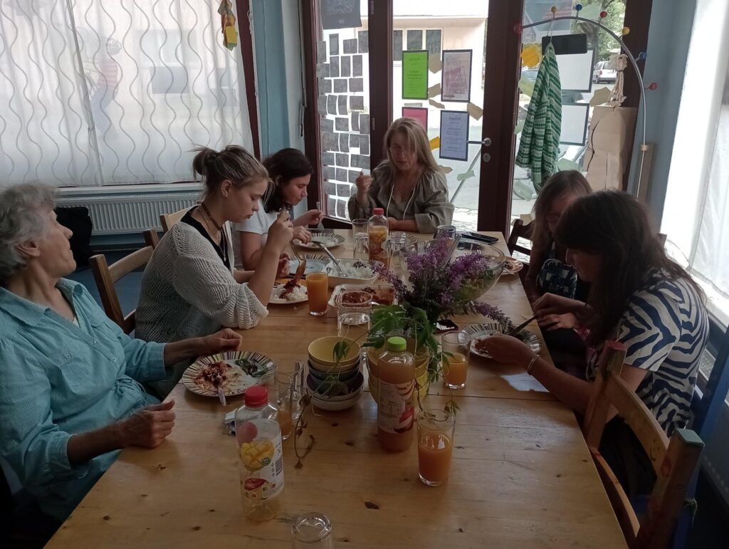 Sechs Frauen sitzen zusammen und essen gemeinsam