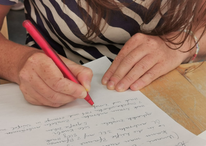 Frau schreibt auf Papier, nur ihre Hände sichtbar