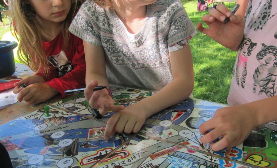 Drei Kinder spielen ein Brettspiel ähnlich Monopoly